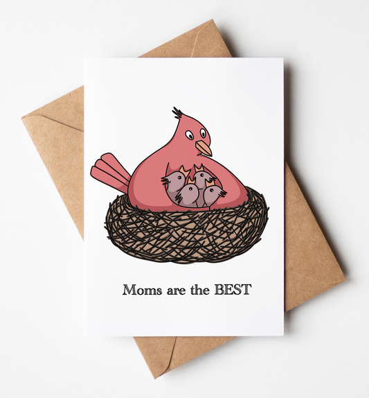 A white greeting card featuring a cartoon illustration of a pink mother bird with three gray chicks in a brown nest, with the text 'Moms are the BEST' printed below. The card is displayed on top of a brown kraft envelope against a clean white background.