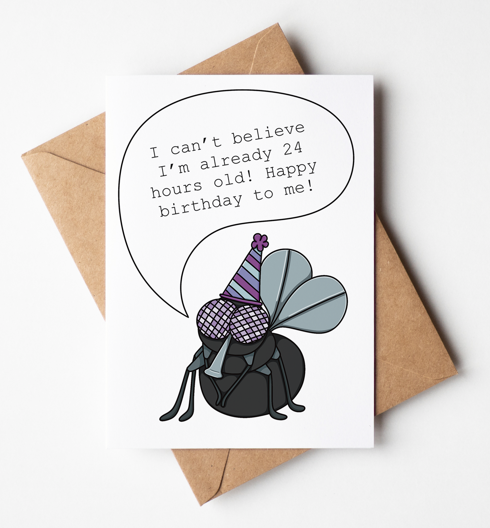 A white greeting card with a brown kraft envelope, featuring a cartoon bug wearing a party hat and a speech bubble that reads, 'I can't believe I'm already 24 hours old! Happy birthday to me!' on a light gray background.