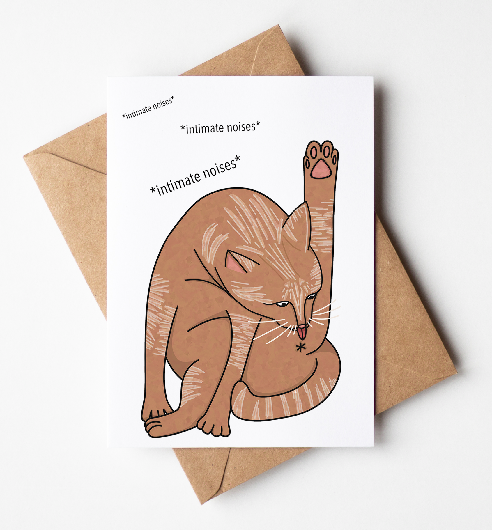 A white greeting card with a brown cartoon cat licking its paw and the text '*intimate noises*' and '*intimate noises*' lies on top of a brown kraft envelope against a clean white background.