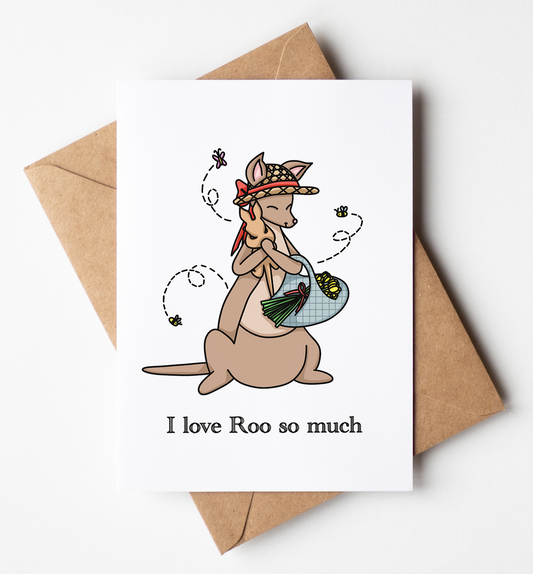 A white greeting card with a cute cartoon kangaroo wearing a hat and holding a basket, with the text 'I love Roo so much' below. The card is displayed on top of a brown kraft envelope against a clean white background.