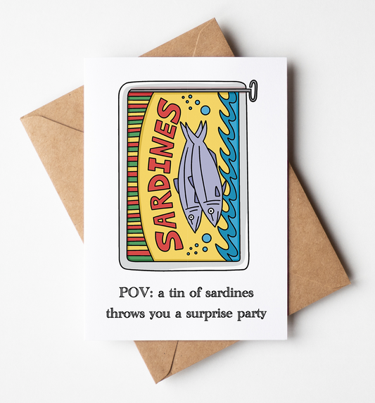 A white greeting card with a colorful tin of sardines illustration and the text 'POV: a tin of sardines throws you a surprise party', shown on top of a brown kraft envelope against a light gray background.