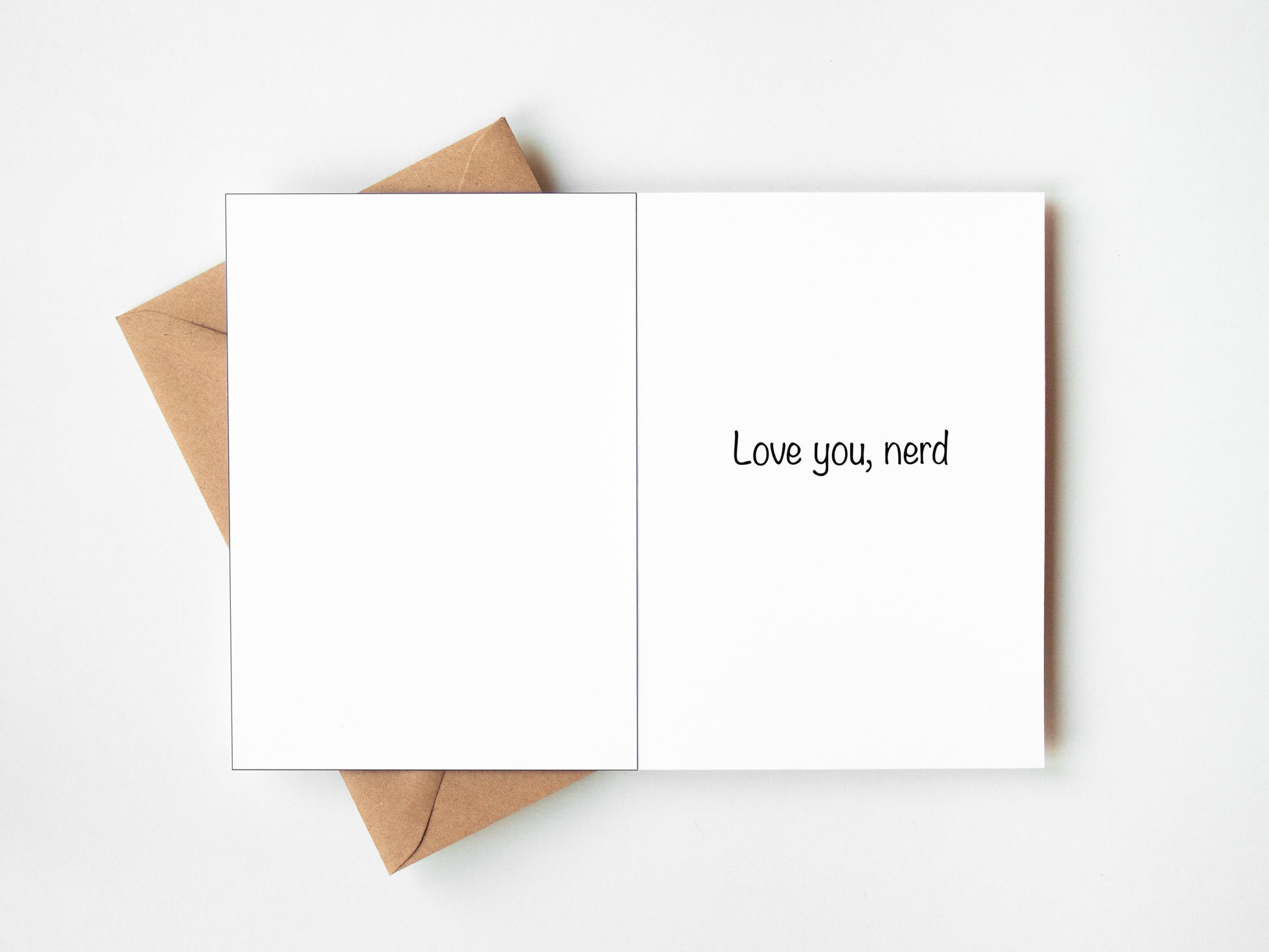 An open white greeting card with the phrase 'Love you, nerd' printed in black on the right panel, layered over a brown kraft envelope on a clean white background.