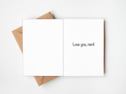 An open white greeting card with the phrase 'Love you, nerd' printed in black on the right panel, layered over a brown kraft envelope on a clean white background.