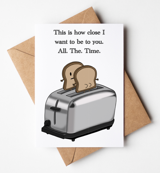 A white greeting card with a humorous quote and an illustration of two slices of toast in a toaster, shown with a brown kraft envelope on a light gray background.
